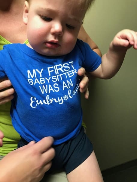 baby wearing a t-shirt with text "my first babysitter was an embryologist", our ivf over 40 success story