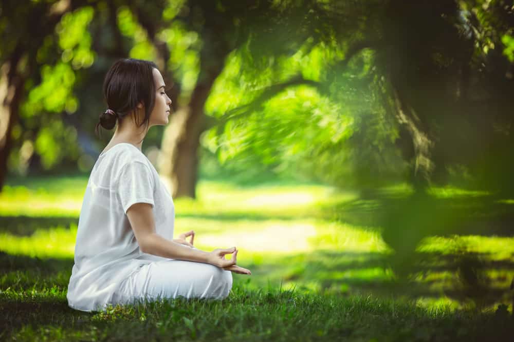 woman in lotus position sitting on grass