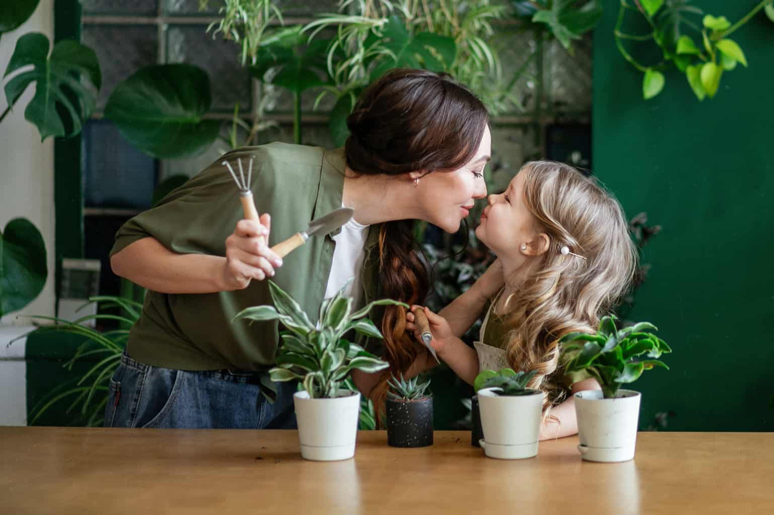 Mother and daughter plant green plants in the greenhouse. A blonde girl and her mother are engaged in gardening. POSITIVE PARENTING TIPS how to be a better parent