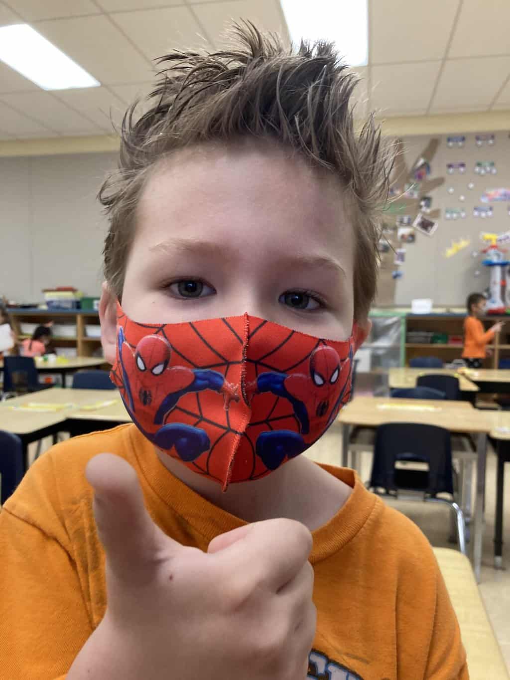 cute toddler boy with spiky haircut wearing a spiderman face mask giving a thumbs up, overcoming child fear of haircuts, haircut phobia