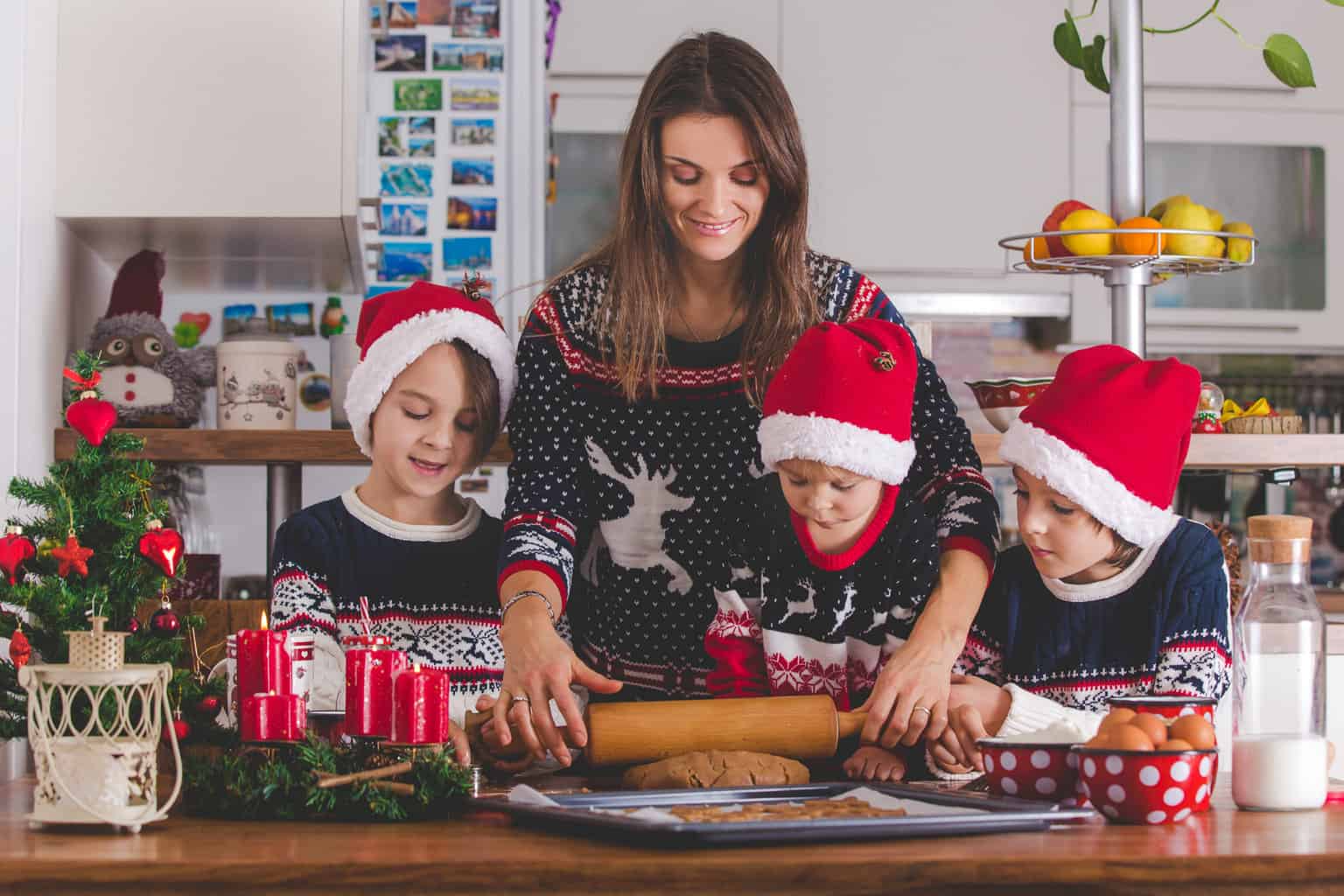 a mom baking christmas cookies with her three happy children, boys, 