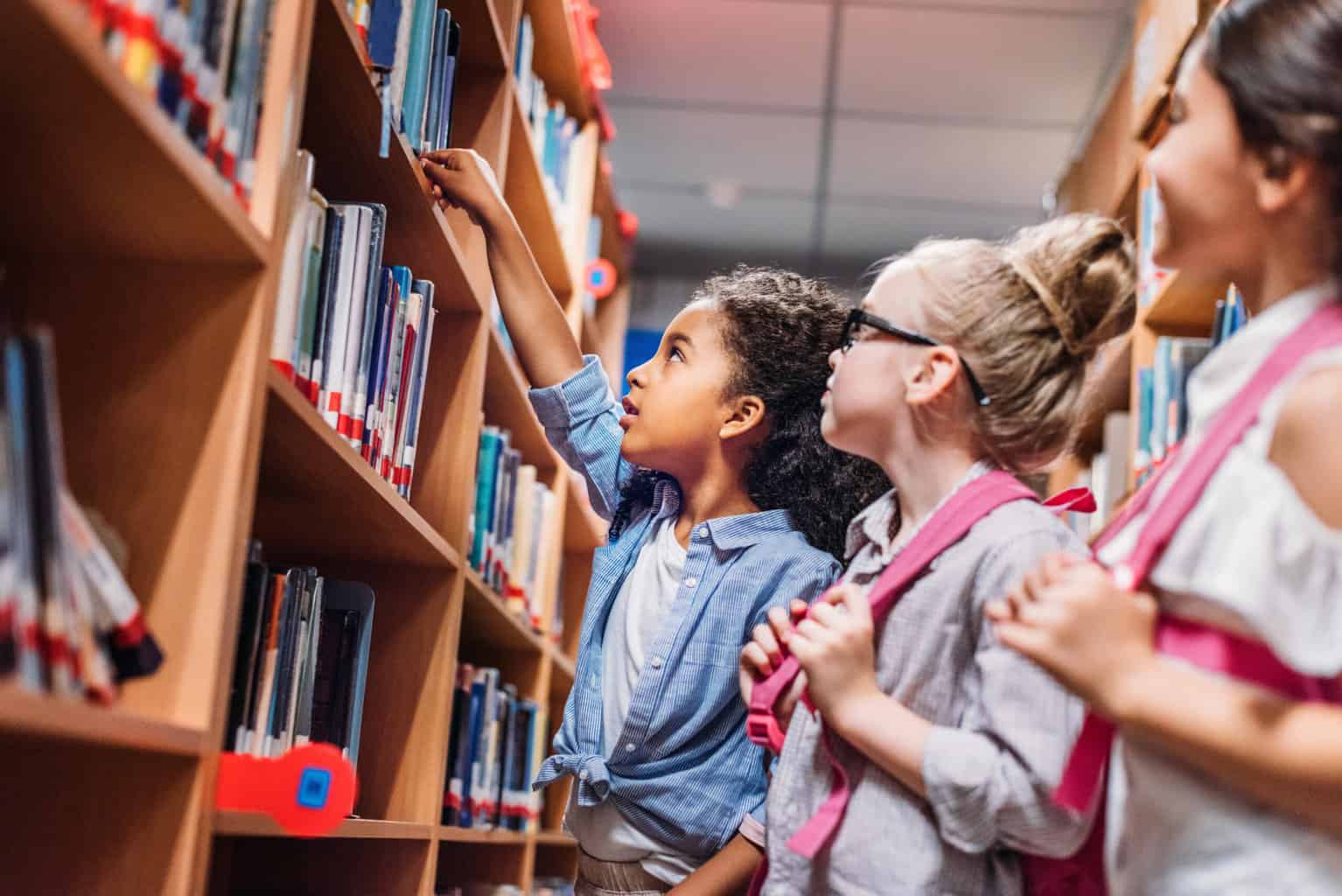 kids looking at bookshelves in library, benefits of library trips for children